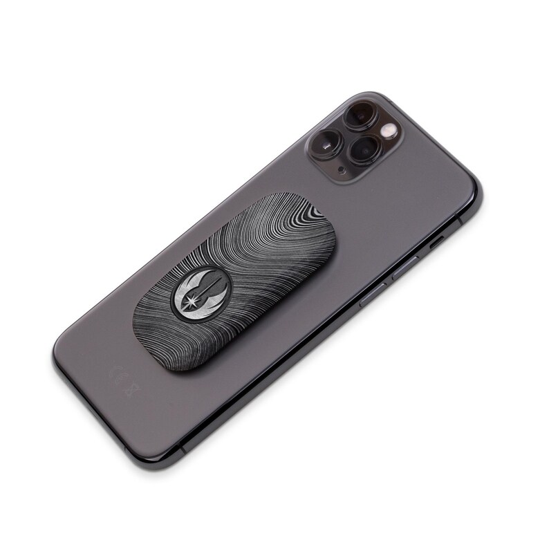 Pu&ograve; includere: Un telefono nero con un'impugnatura per telefono con il logo della Ribellione. L'impugnatura ha un motivo a venature del legno e un logo della Ribellione argentato.