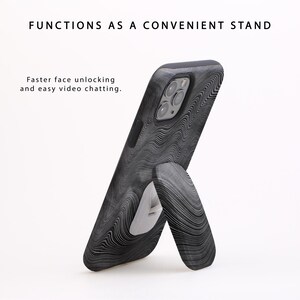 Puede incluir: Una funda de tel&eacute;fono negra con un patr&oacute;n de remolino blanco y negro. La funda tiene un soporte integrado que permite que el tel&eacute;fono se mantenga en posici&oacute;n vertical.