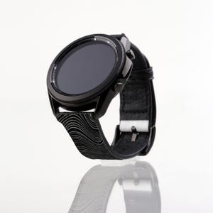 May include: A black smartwatch with a black and white patterned band. The watch face is black and has a digital display.