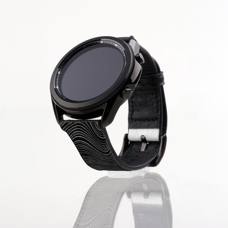May include: A black smartwatch with a black and white patterned band. The watch face is black and has a digital display.