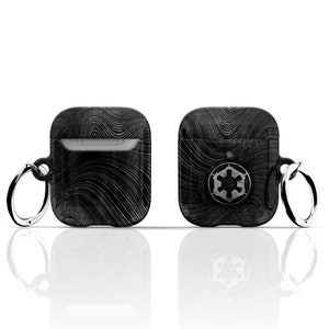 May include: Black Airpods case with a black and white wavy pattern and a silver Imperial symbol on the front. The case has a silver ring attached to it.