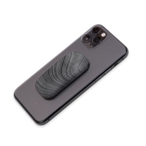Puede incluir: Un tel&eacute;fono negro con un agarre de tel&eacute;fono estampado en blanco y negro pegado en la parte posterior.