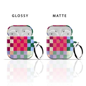 Puede incluir: Dos estuches para Airpods con un patr&oacute;n a cuadros en tonos de rosa, rojo, verde, azul y blanco. El estuche de la izquierda es brillante y el estuche de la derecha es mate. Ambos estuches tienen un peque&ntilde;o anillo met&aacute;lico adjunto.