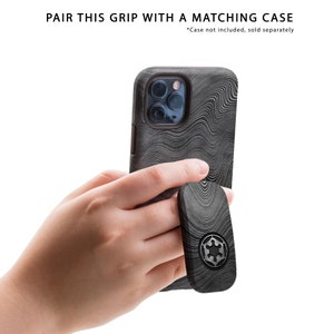 May include: A black and gray phone case and grip set with a wave pattern. The grip features a circular emblem. The text "PAIR THIS GRIP WITH A MATCHING CASE" is at the top.
