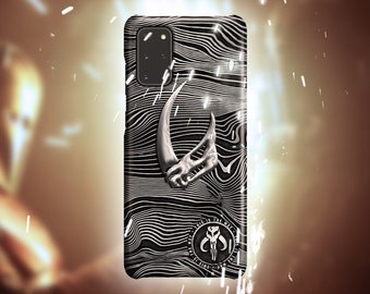 Op de afbeelding: Een zwarte telefoonhoes met een wit en grijs Mandalorian-symbool en de tekst "This is the way" in een cirkel rond het symbool.