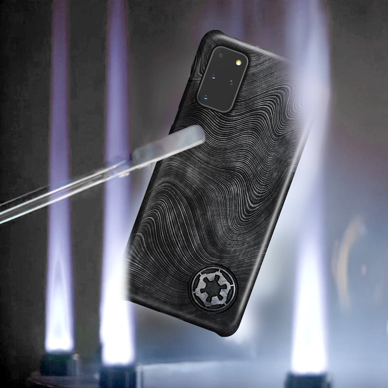 May include: A black phone case with a white, wavy pattern and a black and white symbol in the centre. The case is being held by a pair of hands.