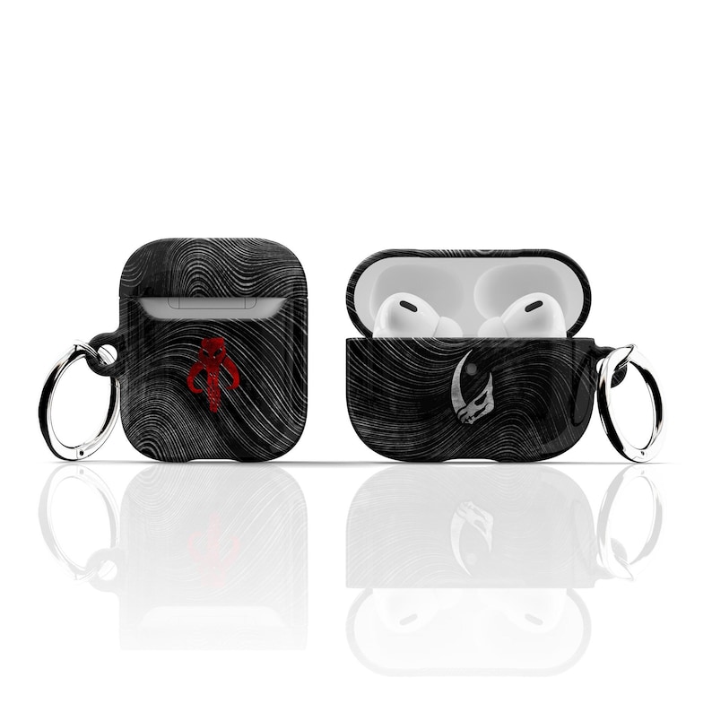 May include: Black and white patterned Airpod case with a red Mandalorian symbol on one side and a white symbol on the other side. The case has a black keychain attached.