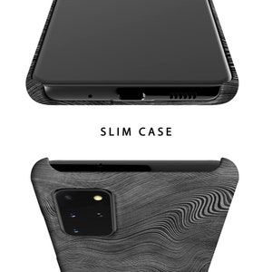 Puede incluir: Una funda de tel&eacute;fono negra con un patr&oacute;n de veta de madera. La funda est&aacute; dise&ntilde;ada para adaptarse a un tel&eacute;fono con una protuberancia de c&aacute;mara y una sola lente de c&aacute;mara.