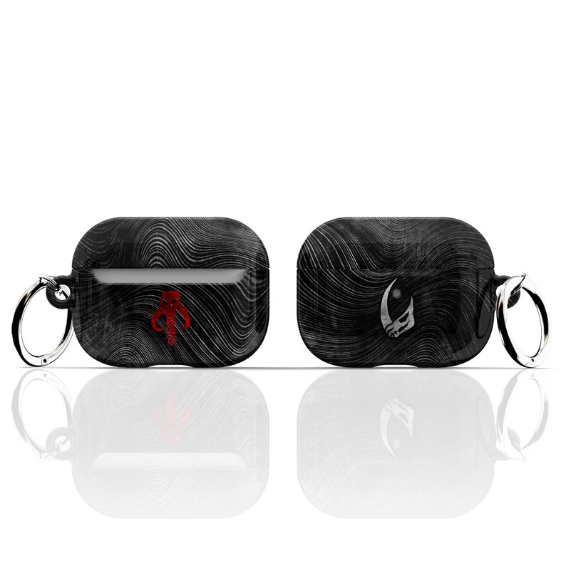 May include: Two black Airpod cases with a textured design. One case features a red Mandalorian symbol and the other a white symbol. Both cases have a silver key ring.