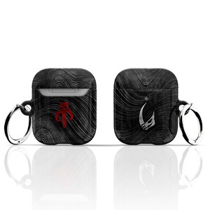 May include: Two black Airpod cases featuring a Mandalorian and a Boba Fett design. Each case has a silver ring attached to the top.