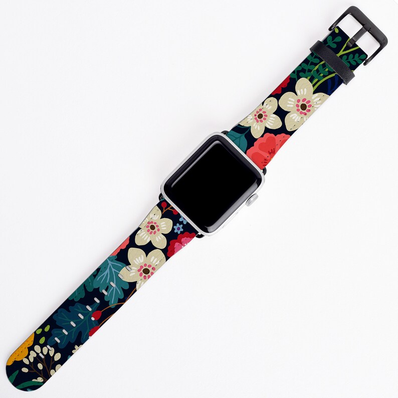 Op de afbeelding: Een zwart horlogebandje met een bloemenpatroon met witte, rode, roze en groene bloemen. Het bandje is compatibel met Apple Watches.