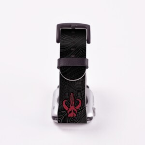 May include: Black Apple Watch band with a red Mandalorian symbol on a black and white wavy pattern.