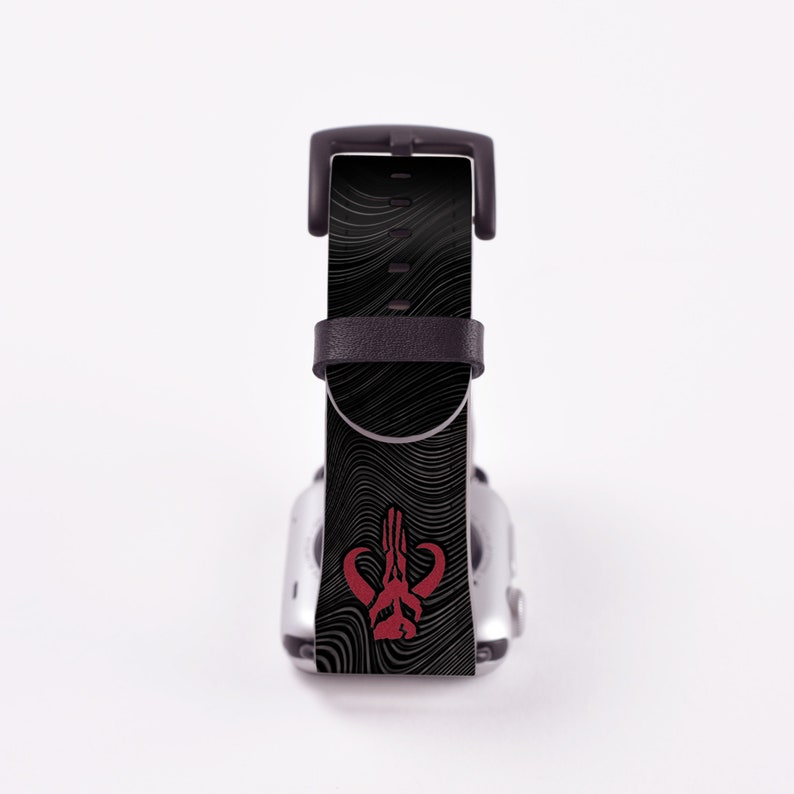 May include: Black Apple Watch band with a red Mandalorian symbol on a black and white wavy pattern.
