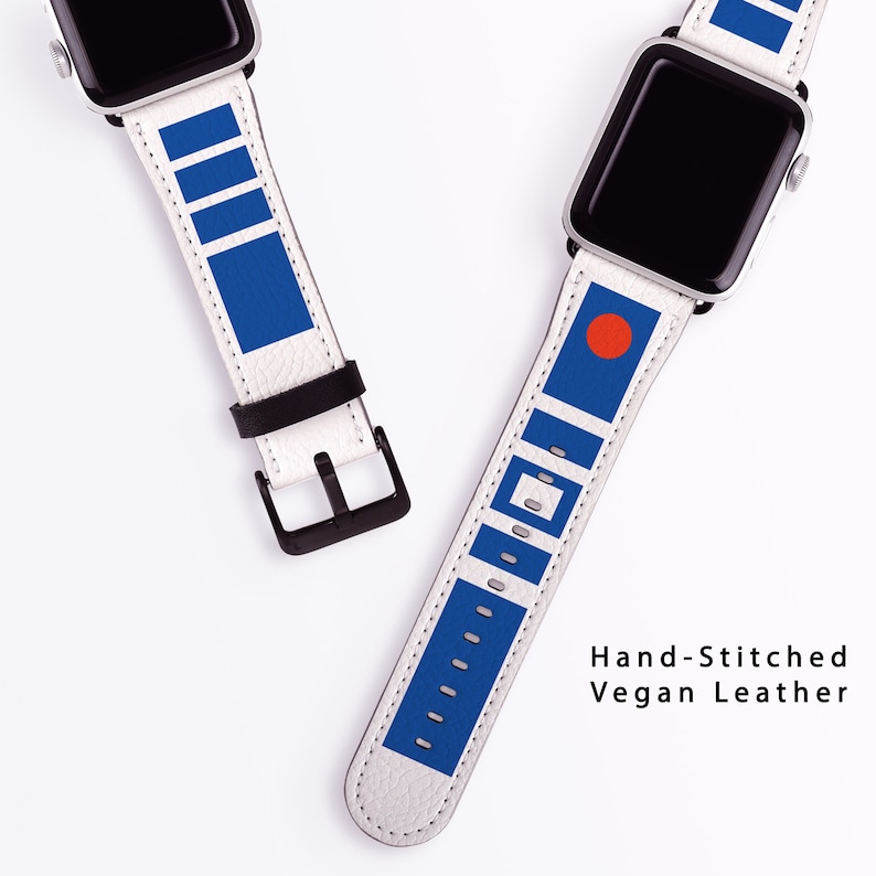 May include: Two white Apple Watch bands with blue and red accents. The bands are made of vegan leather and are hand-stitched. The text "Hand-Stitched Vegan Leather" is printed below the bands.
