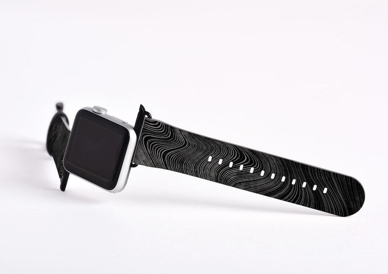 May include: A black and white patterned Apple Watch band with a silver Apple Watch.