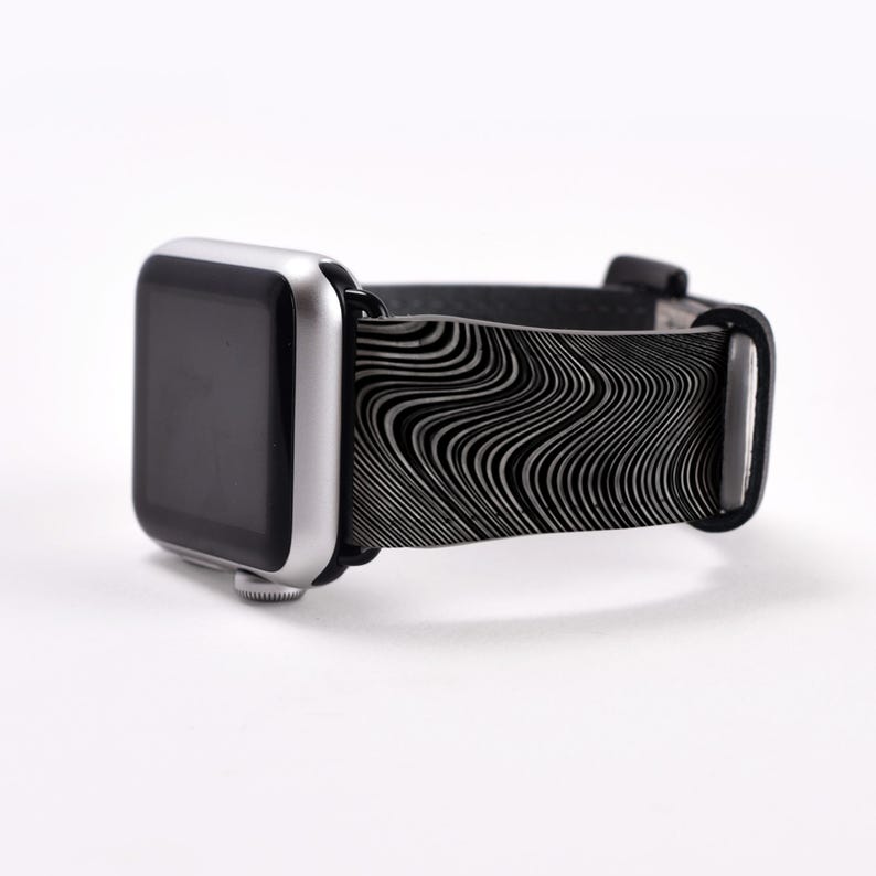 May include: A black and white patterned Apple Watch band with a silver Apple Watch.