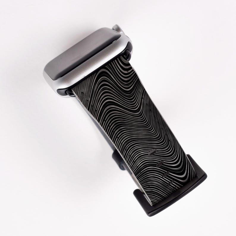 May include: A black and silver Apple Watch band with a wavy, abstract pattern.