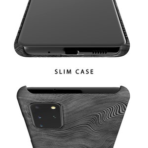 May include: A black phone case with a wood grain pattern. The case is designed to fit a phone with a camera bump. The text "SLIM CASE" is printed on the case.