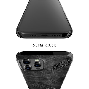 May include: A black phone case with a wood grain pattern. The case has a raised camera bump and a cutout for the phone's charging port. The text "SLIM CASE" is printed on the case.