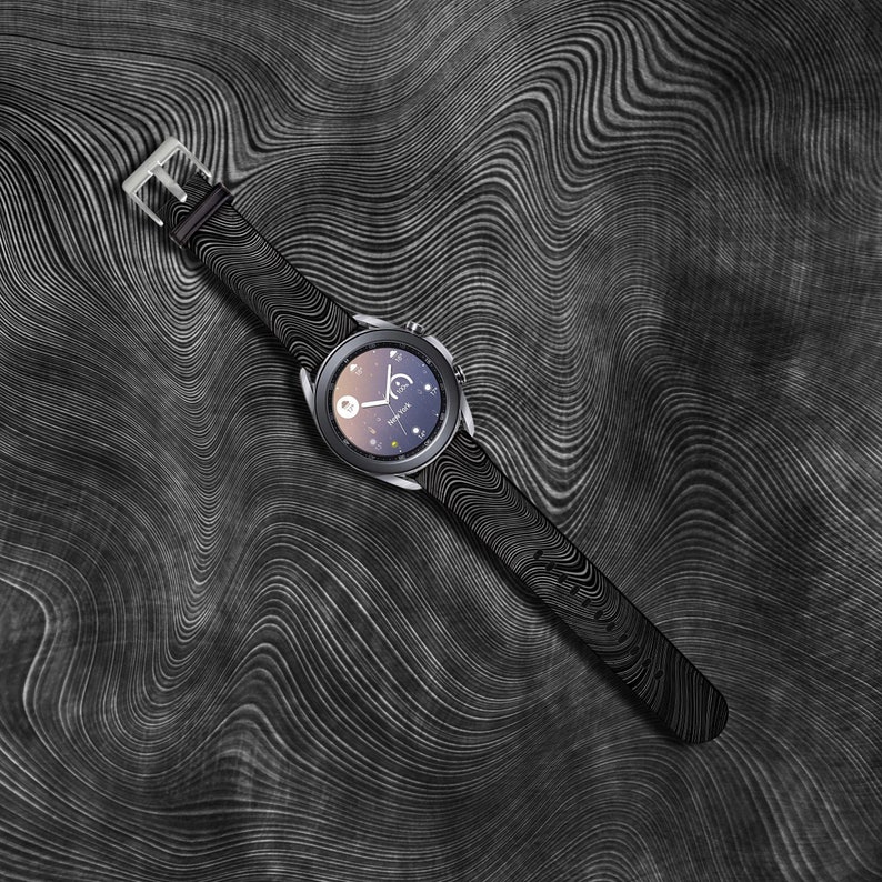 May include: A black smartwatch with a black patterned band on a black and white wavy background.