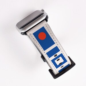 May include: A white Apple Watch band with a blue and red geometric pattern. The band is made of leather and has a silver buckle.