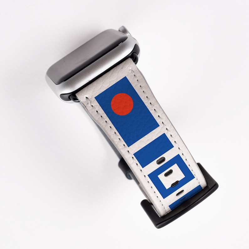 May include: A white Apple Watch band with a blue and red geometric pattern. The band is made of leather and has a silver buckle.