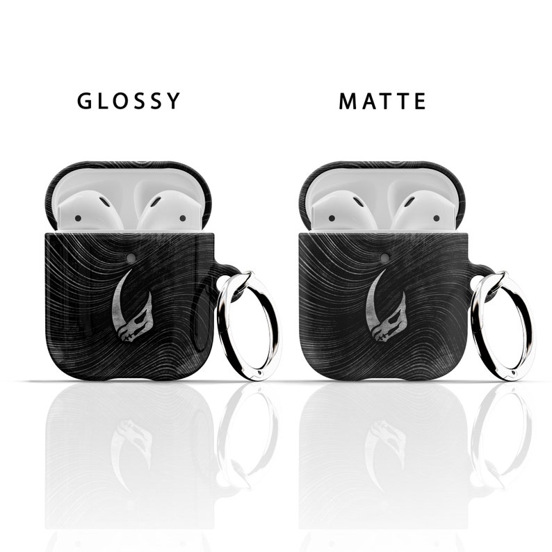 May include: Two black Airpod cases with a white graphic of a horned creature. One case is glossy and the other is matte. Both cases have a silver ring attached.