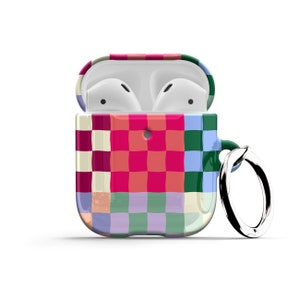 Puede incluir: Una funda con estampado de cuadros de colores para Apple AirPods con un anillo de metal adjunto. La funda est&aacute; abierta para revelar los AirPods blancos en el interior.