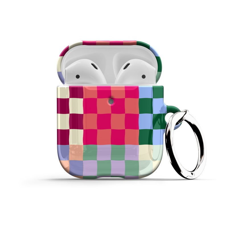 Puede incluir: Una funda con estampado de cuadros de colores para Apple AirPods con un anillo de metal adjunto. La funda est&aacute; abierta para revelar los AirPods blancos en el interior.