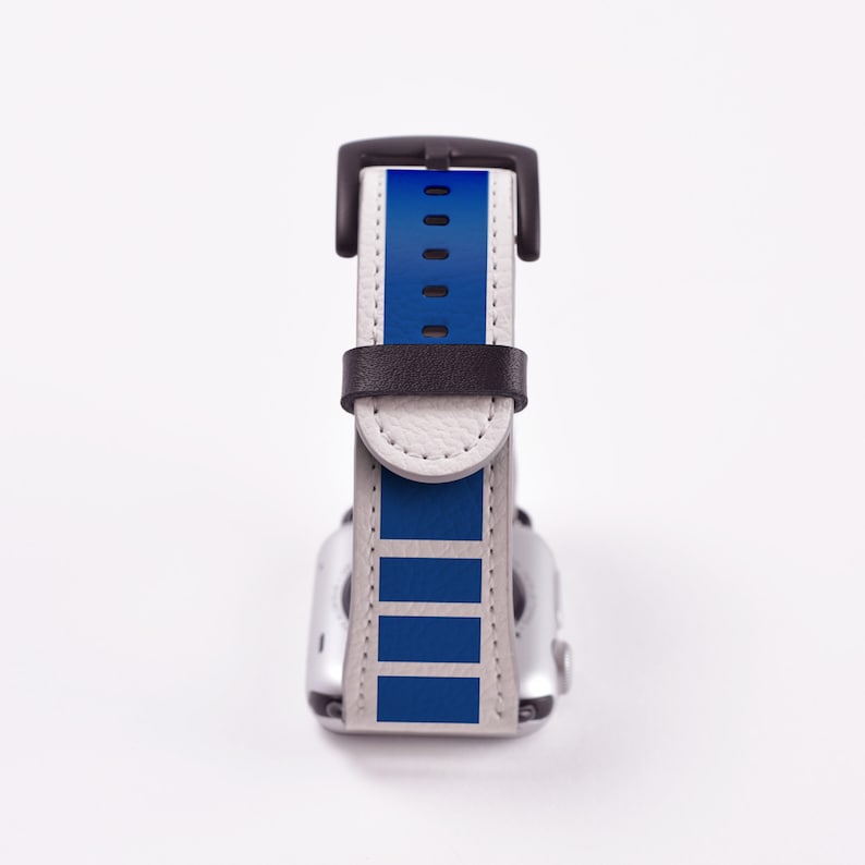 May include: A white and blue Apple Watch band with a black buckle. The band has a blue stripe pattern.