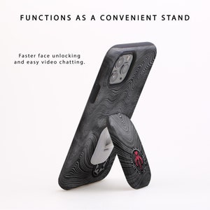 May include: A black phone case with a white and black swirl pattern. The case has a built-in kickstand that can be used to prop up the phone for hands-free viewing.