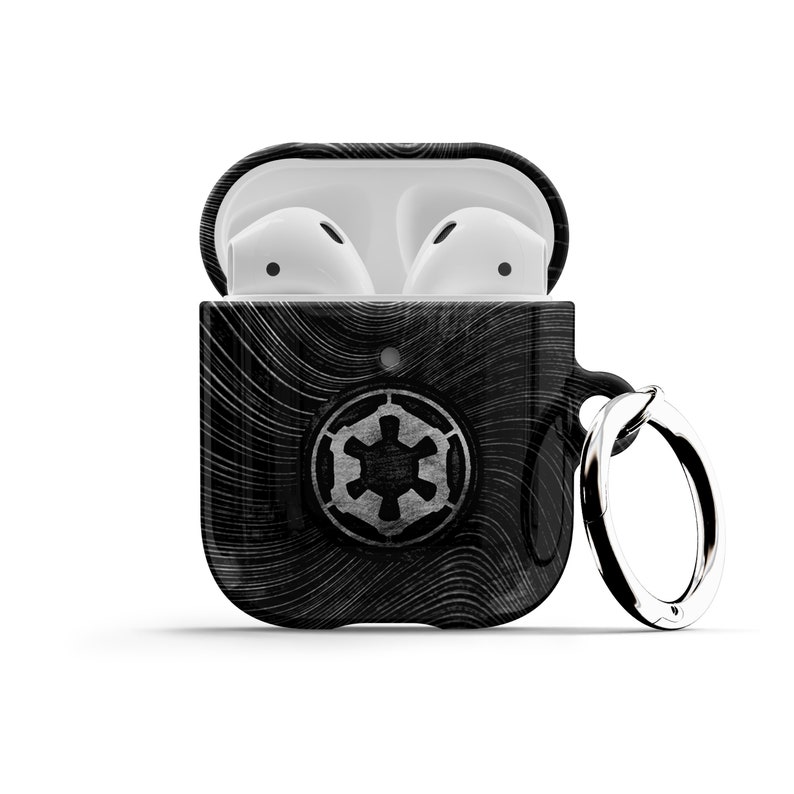 May include: Black and white AirPods case with a black and white Imperial symbol from Star Wars. The case has a black and white wood grain pattern and a silver key ring.