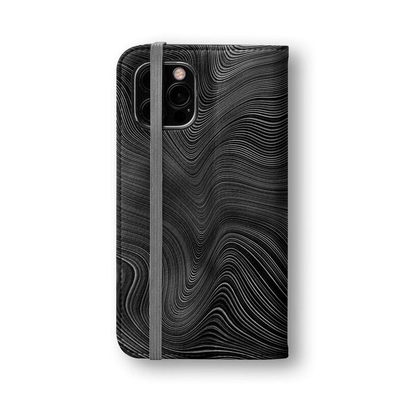 Może przedstawiać: Czarne sk&oacute;rzane etui na telefon z falistym, abstrakcyjnym wzorem linii. Etui ma czarny pasek.