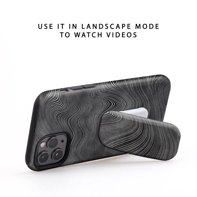 Puede incluir: Funda de tel&eacute;fono negra con un patr&oacute;n de remolino blanco y un soporte integrado. "USE IT IN LANDSCAPE MODE TO WATCH VIDEOS" est&aacute; escrito en blanco sobre un fondo blanco.