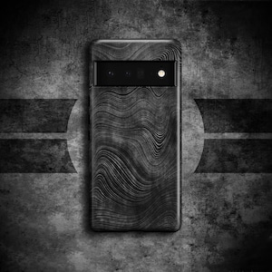 Puede incluir: Una funda de teléfono negra con un patrón ondulado abstracto. La funda tiene un recorte para el objetivo de la cámara en la parte posterior.