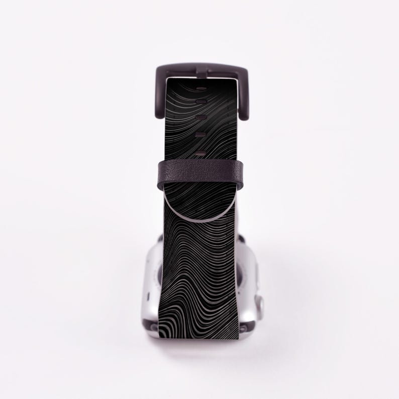 May include: Black and white patterned watch band with a black leather strap. The band is designed for a smartwatch.