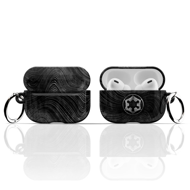 May include: Black and white patterned Airpods case with a silver keychain and the Star Wars Imperial symbol. The case is open and the white Airpods are visible inside.