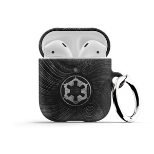 May include: Black and white Airpods case with a Star Wars Imperial logo and a silver key ring. The case is open and the white Airpods are visible inside.