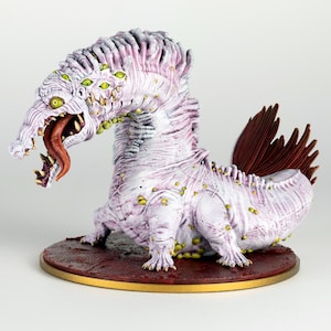 May include: A detailed figurine of a fantastical creature with a pale purple and white body, multiple yellow eyes, and a long, red tongue. The creature has a spiky dorsal fin and is posed on a circular, reddish-brown base with a gold rim.