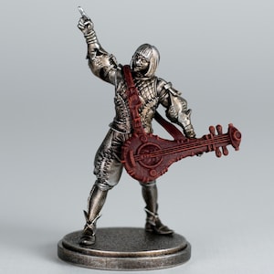 May include: A silver figurine of a musician playing a lute. The figure is wearing detailed armour and a red strap across the chest. The lute is a deep red colour. The figurine is standing on a circular base, with one arm raised.