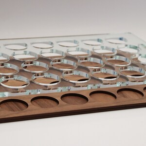 May include: A clear acrylic tray with 24 circular cutouts sits on top of a wooden tray with 12 circular cutouts. Both trays are made of wood.