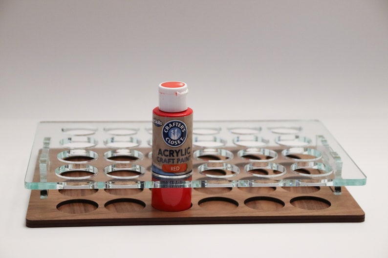 May include: A red acrylic craft paint bottle in a clear acrylic paint organizer with a wooden base. The bottle has a white lid and the label reads "Crafter's Closet Acrylic Craft Paint Red".