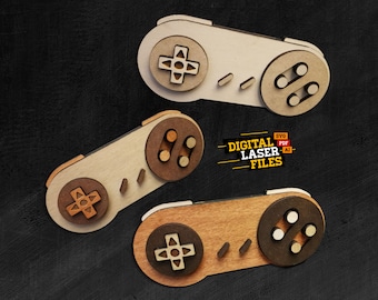 Könnte beinhalten: Drei aus Holz gelaserte Nintendo Super Nintendo Controller-Designs. Die Controller sind in verschiedenen Brauntönen gehalten und haben das klassische Tastenlayout. Der Text "DIGITAL LASER FILES" ist in Gelb auf schwarzem Hintergrund.