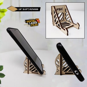 May include: A wooden phone stand with a geometric design. The stand is made of 1/8 inch (0.1377) plywood and is designed to hold a smartphone in a vertical position. The stand is made of natural wood and has a light brown color. The stand is labeled with the FSC logo.