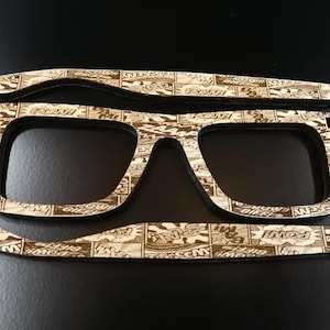 Puede incluir: Un par de gafas de madera con un dise&ntilde;o de impresi&oacute;n de c&oacute;mic. Las gafas est&aacute;n hechas de madera cortada con l&aacute;ser y tienen un acabado marr&oacute;n.