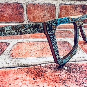 Puede incluir: Un par de gafas de estilo c&oacute;mic azul y marr&oacute;n con montura rectangular. Las gafas est&aacute;n hechas de madera y tienen un dise&ntilde;o &uacute;nico.