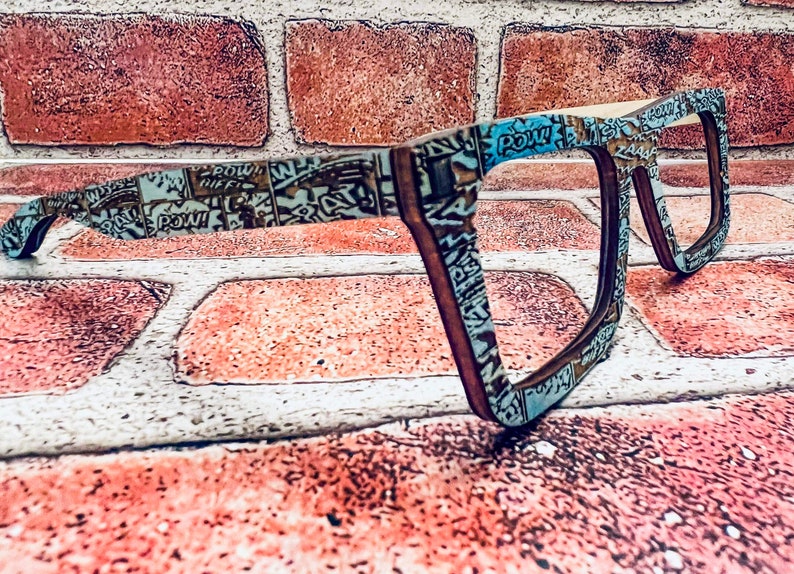 Puede incluir: Un par de gafas de estilo c&oacute;mic azul y marr&oacute;n con montura rectangular. Las gafas est&aacute;n hechas de madera y tienen un dise&ntilde;o &uacute;nico.