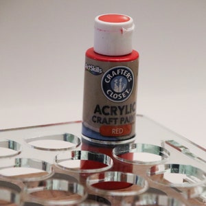 May include: A small bottle of red acrylic craft paint with a white lid and label. The label says "Crafter's Closet" and "Acrylic Craft Paint" in black text. The word "Red" is printed in white text on a blue background.