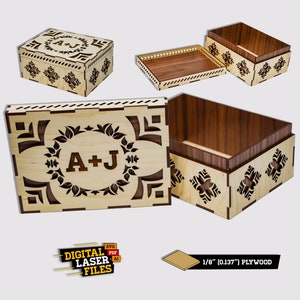 Op de afbeelding: Een houten doos met een lasergesneden ontwerp met een krans met de initialen "A+J". De doos is gemaakt van 1/8 inch multiplex en heeft een deksel dat opengaat om een lege binnenkant te onthullen.