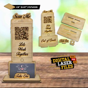 Op de afbeelding: Een houten telefoonstandaard van 1/8 inch multiplex, met een QR-code en de tekst "Scan Me" en "Let's Work Together". De standaard is ontworpen om visitekaartjes te houden en heeft een "Take One" bord.